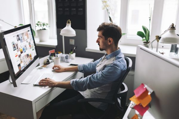 Young man working on computer while sitting at his working place in office