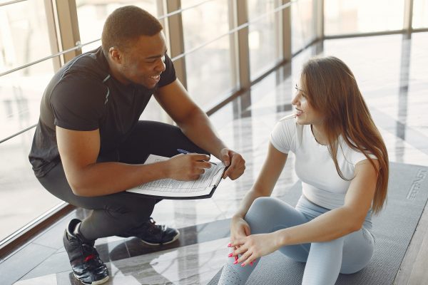 Handsome black man in a gym. Sportspeople in a sportswear. Woman training with coach